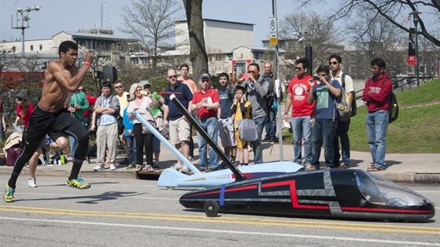 male student pushing a buggy uphill